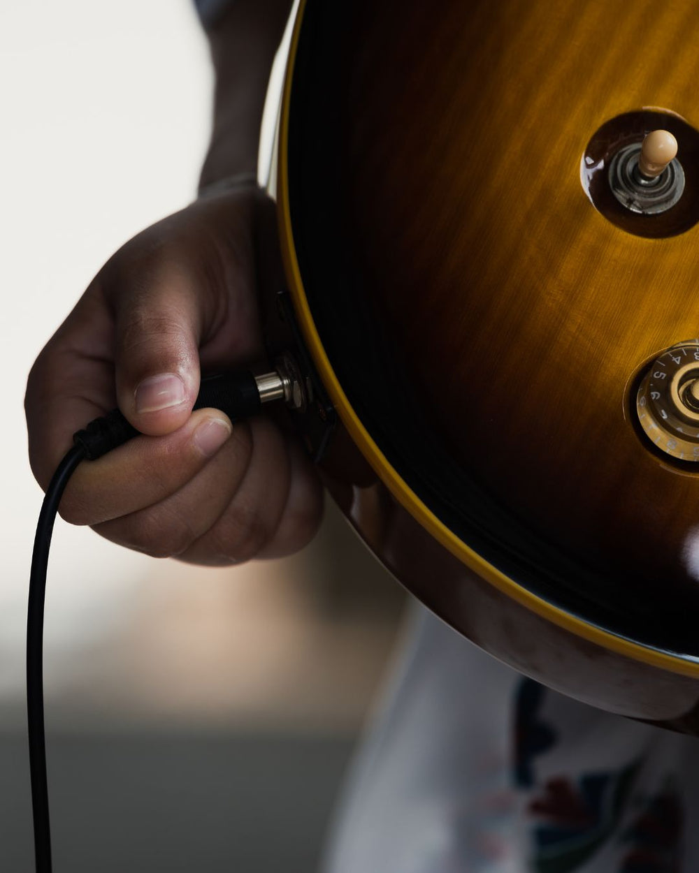 Hand plugging a cable into an electric guitar