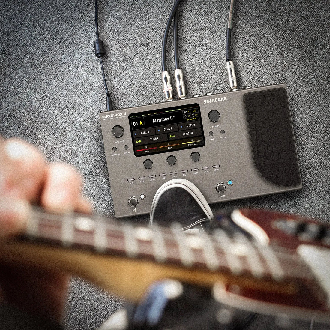 Guitar effects processor with cables on a gray textured background