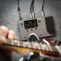 Guitar effects processor with cables on a gray textured background