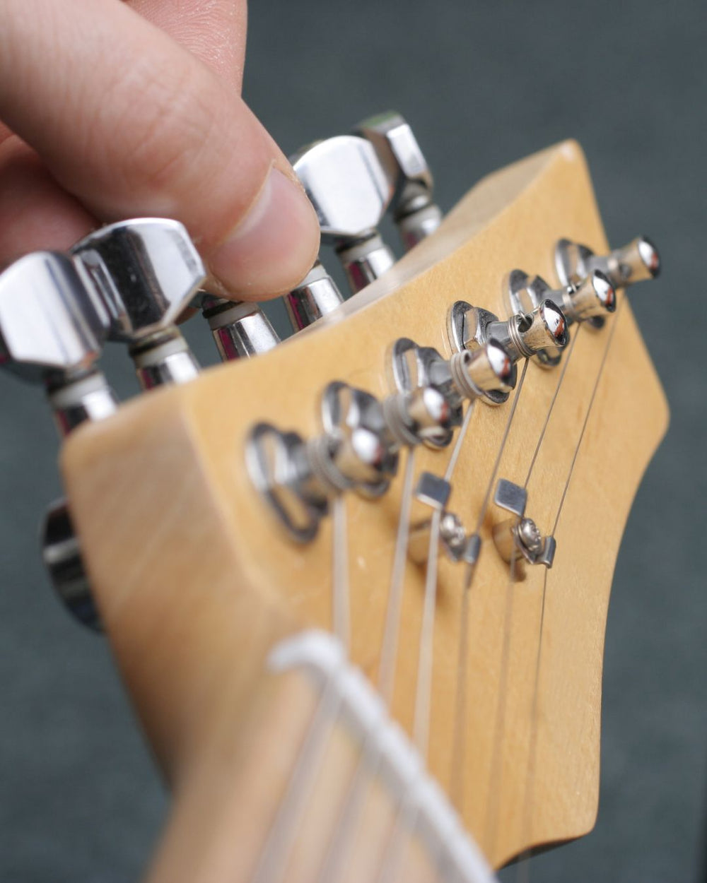 Close-up of a guitar headstock with tuning pegs and strings.