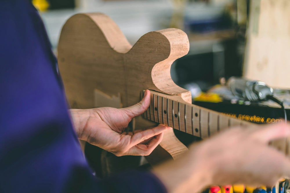 A man is assembling a guitar body and neck
