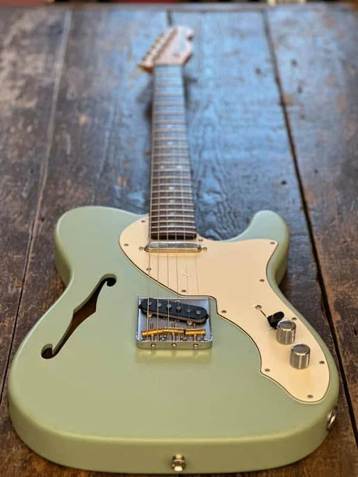Green electric guitar on a wooden surface